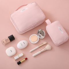 Makeup set with pink pouches and various cosmetic items on a pink background