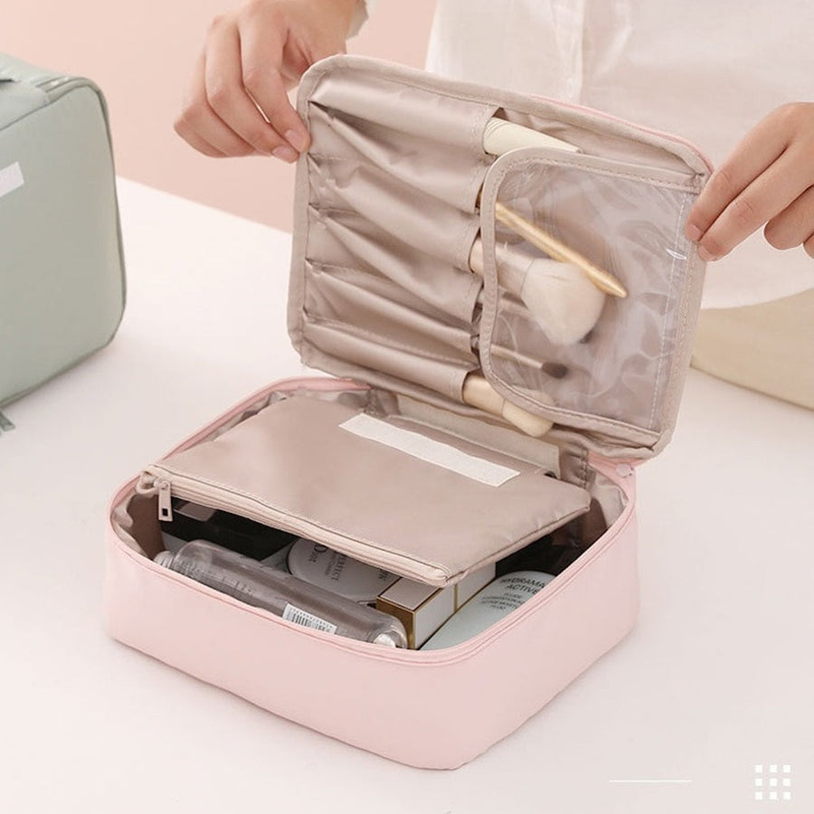 Pink travel makeup case with cosmetic items on a white surface