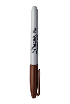 Sharpie marker with brown cap and white body on a brown background
